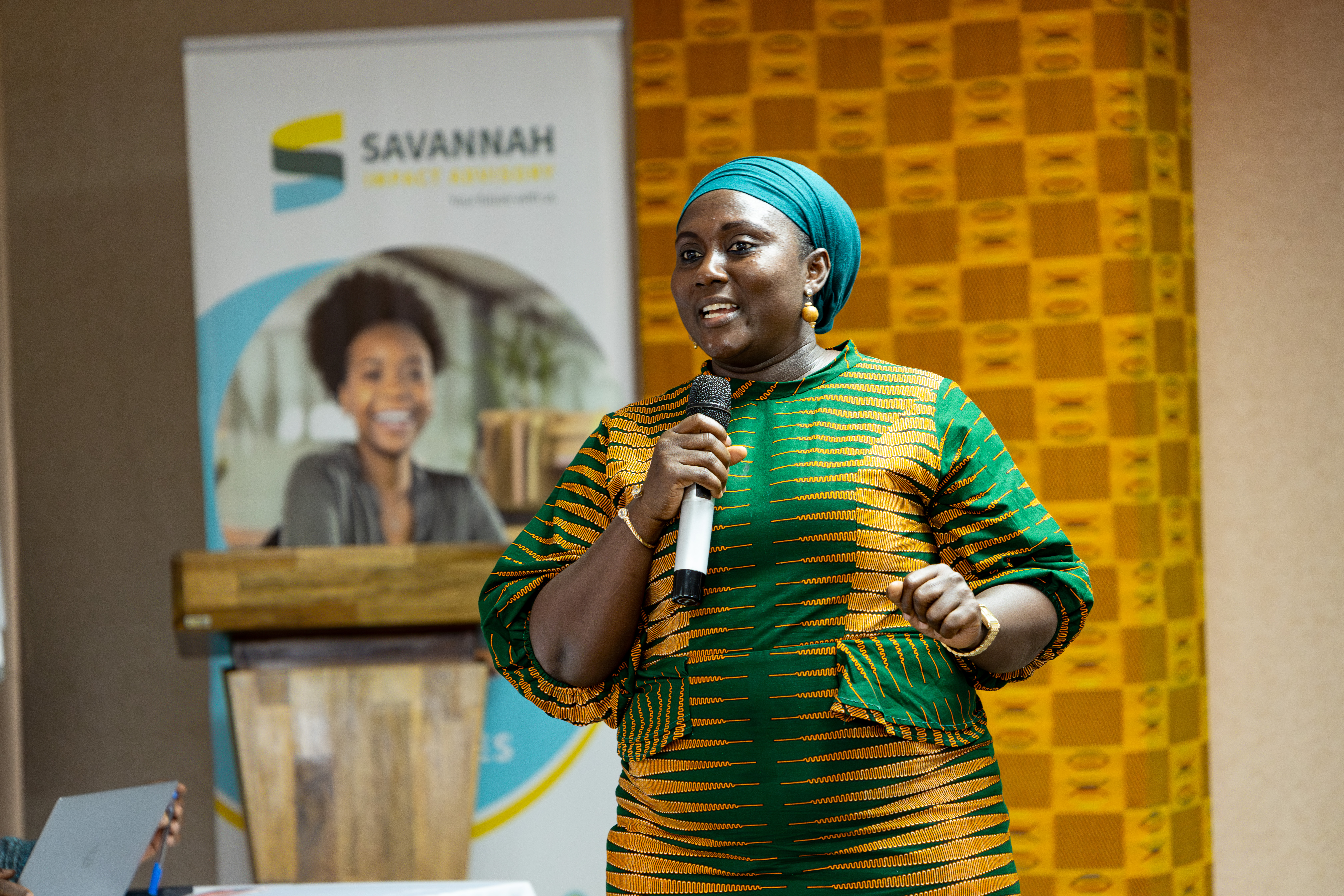Speaker presenting at a Savannah Impact Advisory event with branded backdrop